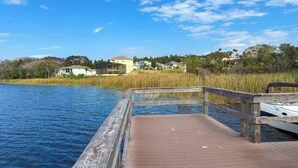 A wooden dock extending into a body of water with houses in the background.