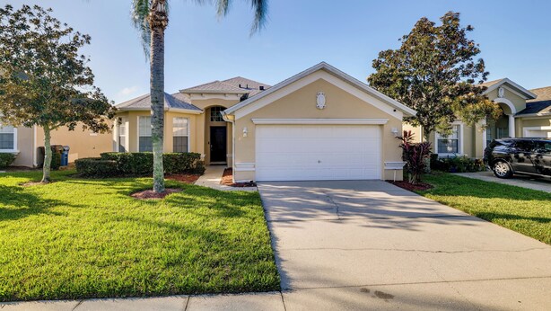 A residential house with a garage, a well-maintained lawn, and a palm tree.