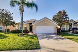 A residential house with a garage, a well-maintained lawn, and a palm tree. - Lake Access & Lanai: Haines City Family Home! (Haines City)