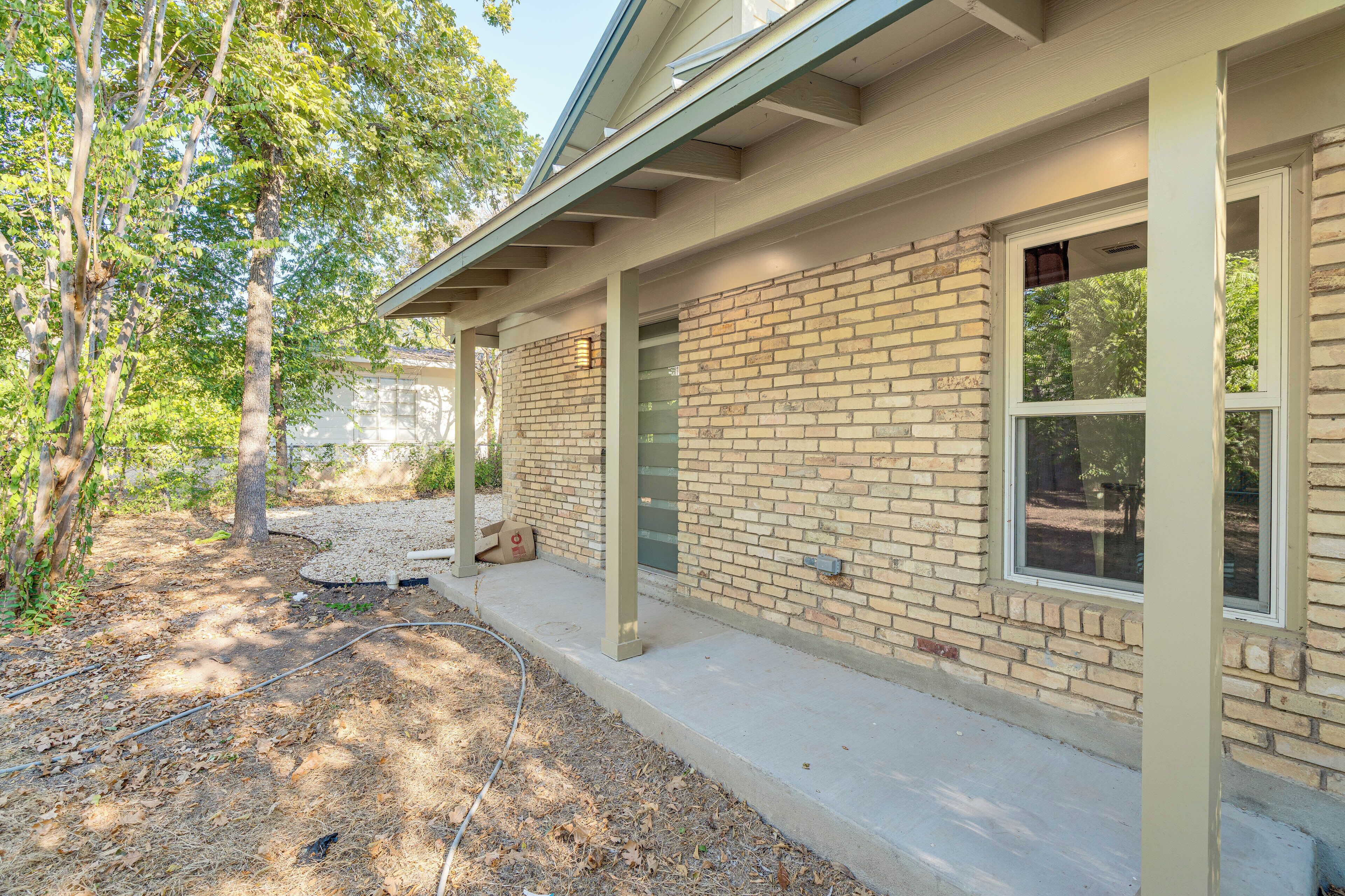 A residential building with a brick exterior, large windows, and a covered porch area.