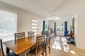 A dining area with a wooden table and chairs, a sofa, and a small side table with a lamp. - 4 Mi to UT Austin: Bright & Modern Family Home (Austin)