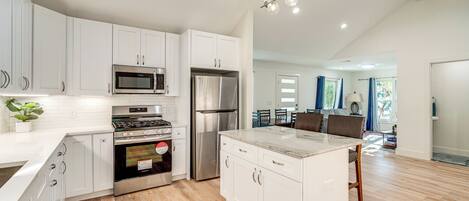A modern kitchen with white cabinets, stainless steel appliances, and a central island.