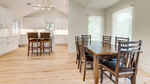 Une cuisine spacieuse avec des meubles blancs, une table à manger en bois et des chaises.