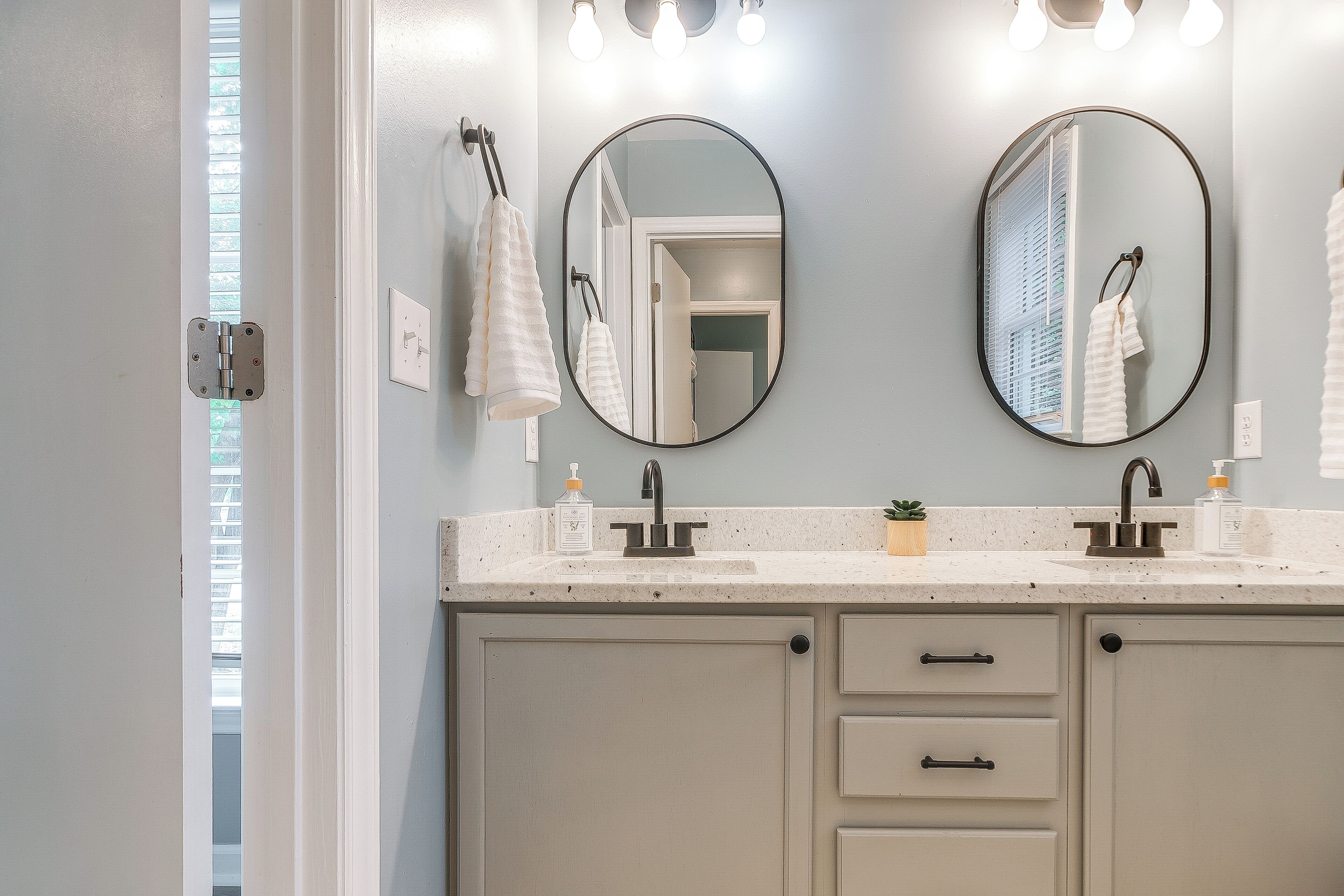 A bathroom with a double sink, two mirrors, and a towel rack.
