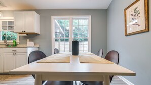 A dining area with a white table, black chairs, and a window with a view of greenery. - Home w/ Pet-friendly Yard, 1 Mi to Dtwn Raleigh! (Raleigh)