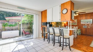 A kitchen with a large island, bar stools, and a dining table.