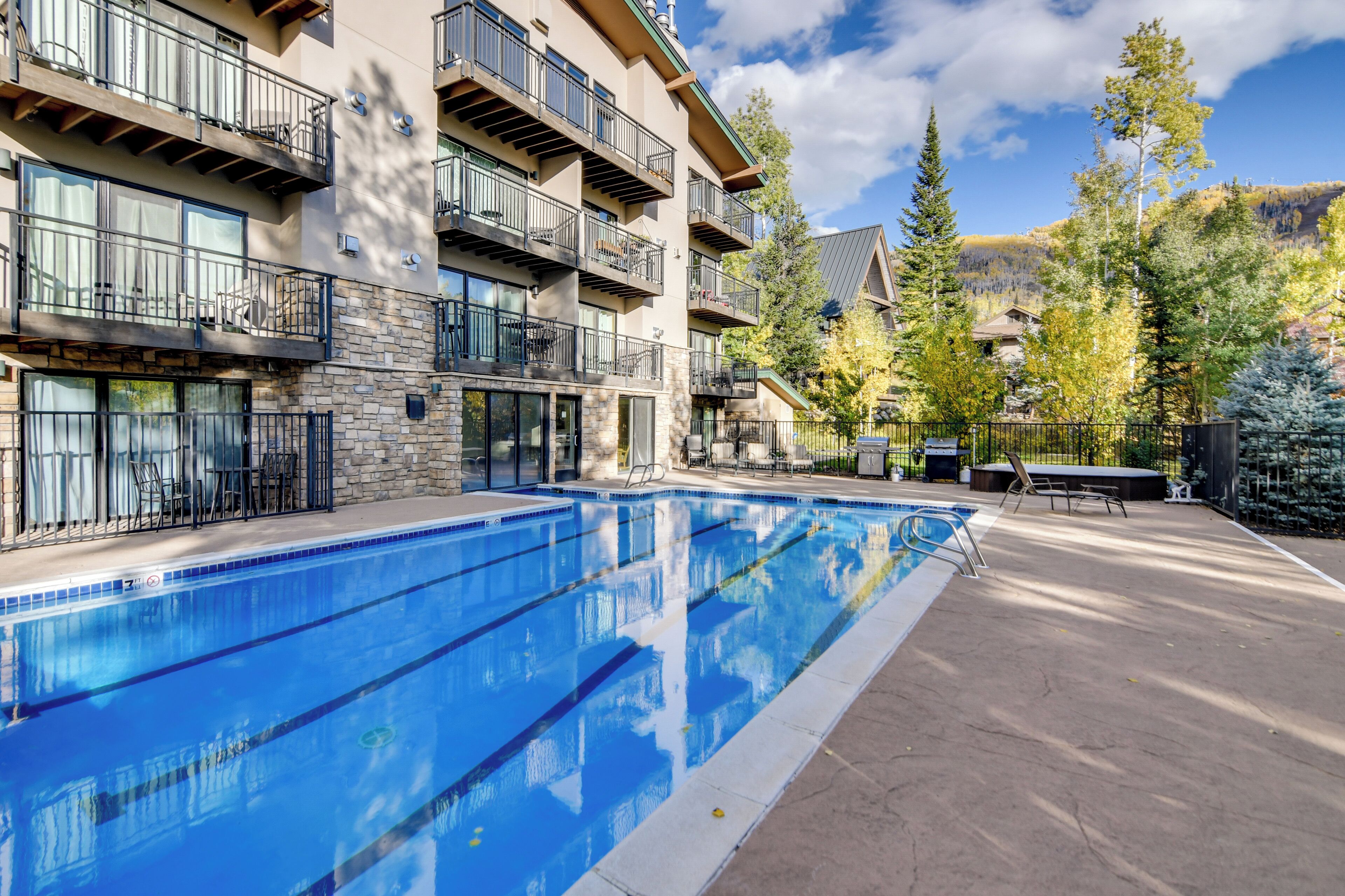 Ein mehrstöckiges Hotel mit Swimmingpool, Außenbereich und Bergblick.