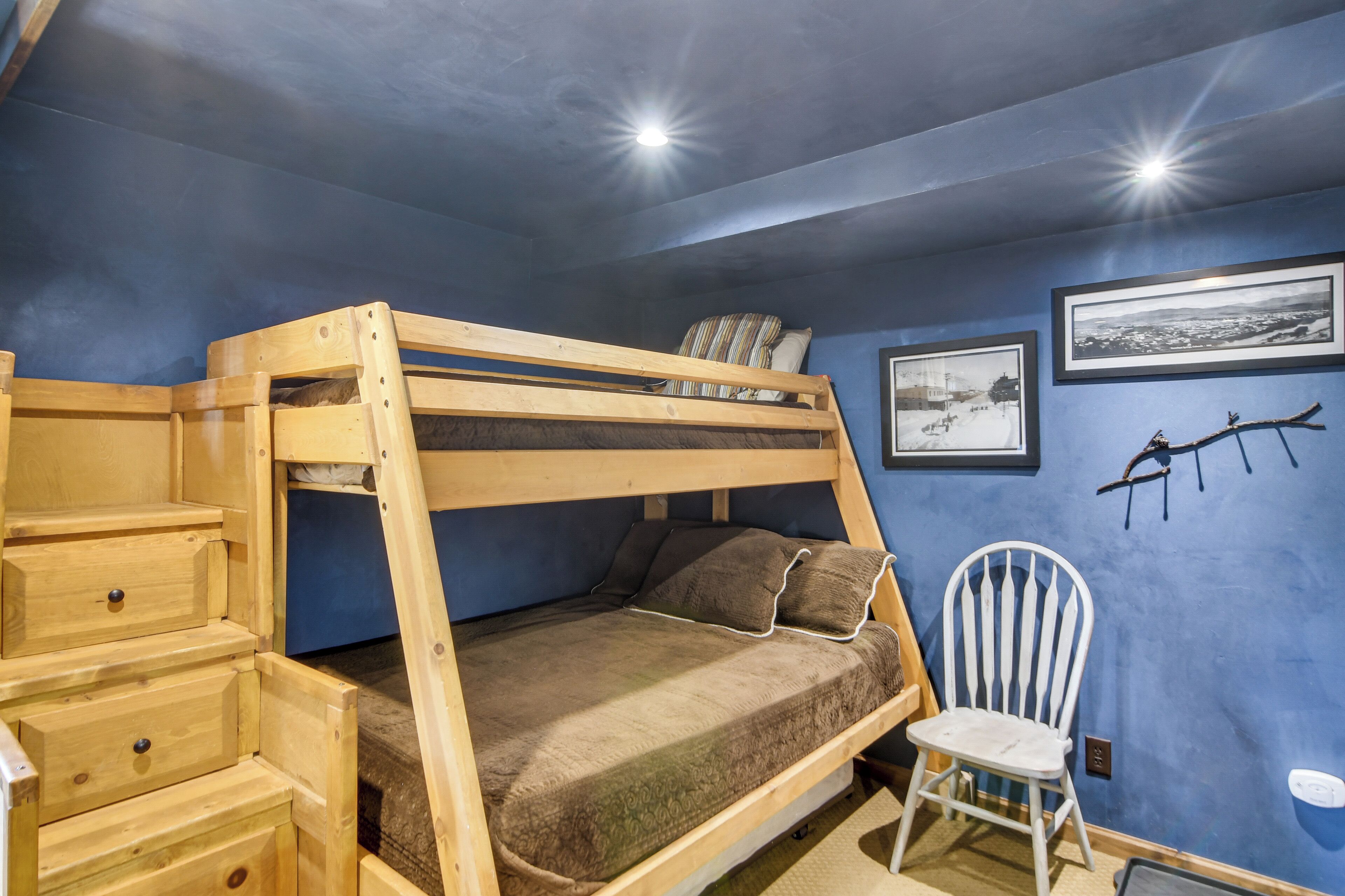 Un lit superposé avec une structure en bois, une petite chaise et une commode avec des tiroirs.