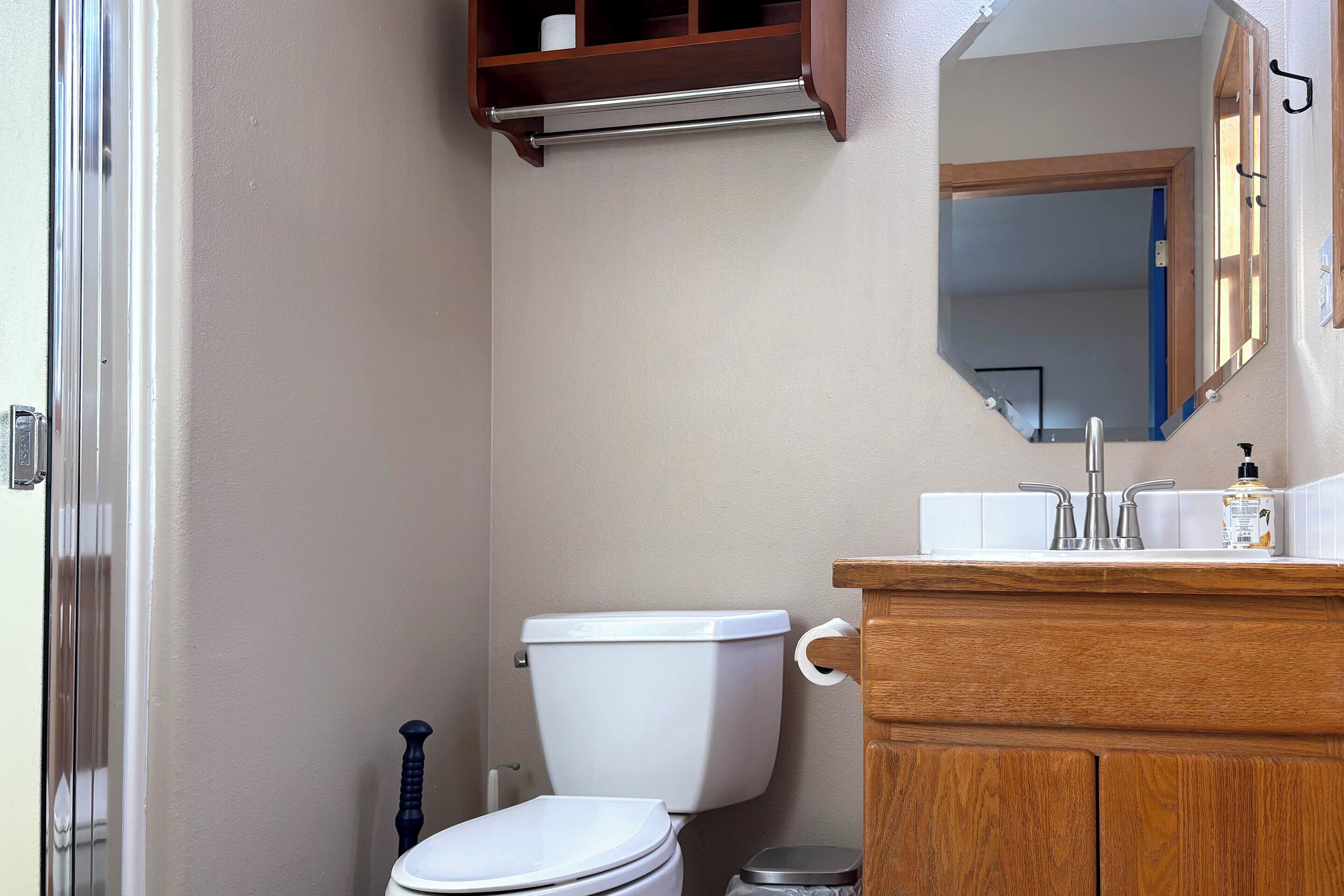 A bathroom with a toilet, sink, and mirror.