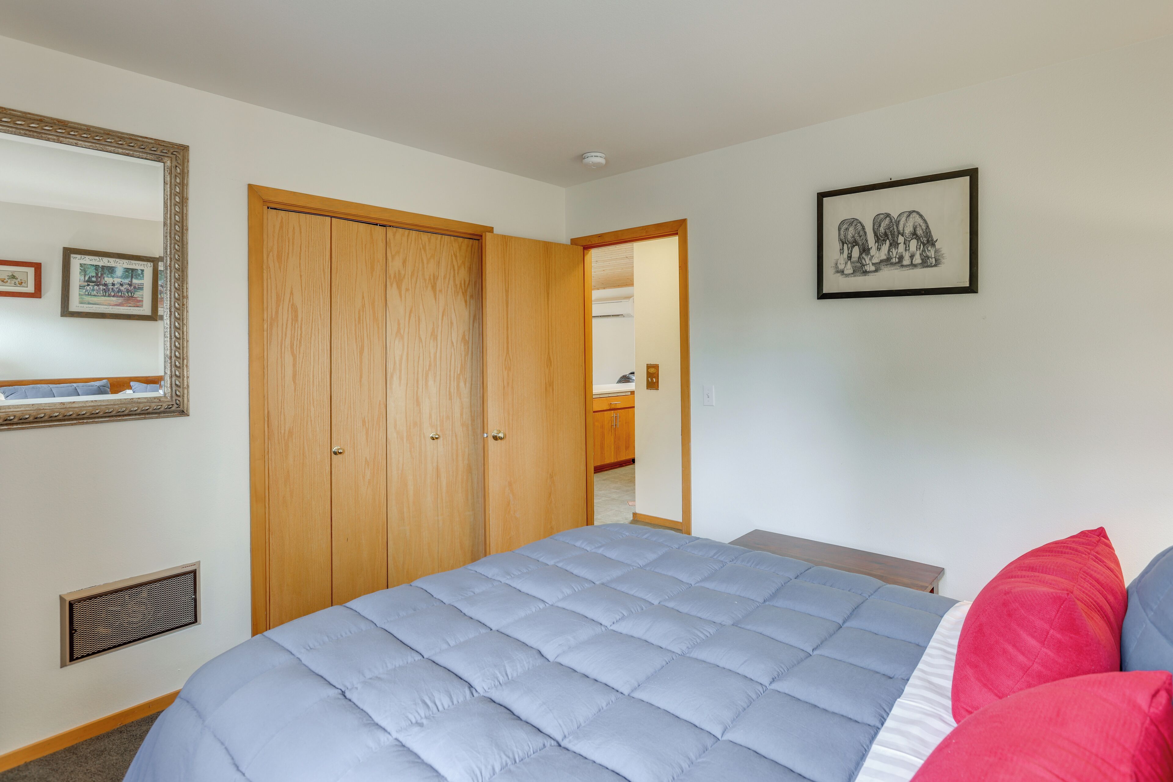 A bedroom with a large bed, a wardrobe, a mirror, and a framed picture on the wall.