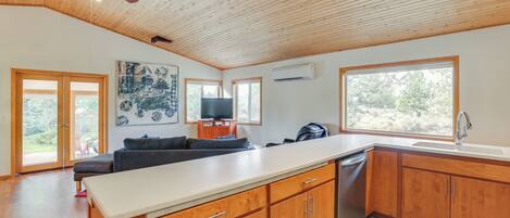A modern kitchen with wooden cabinets, a central island, and a ceiling fan.