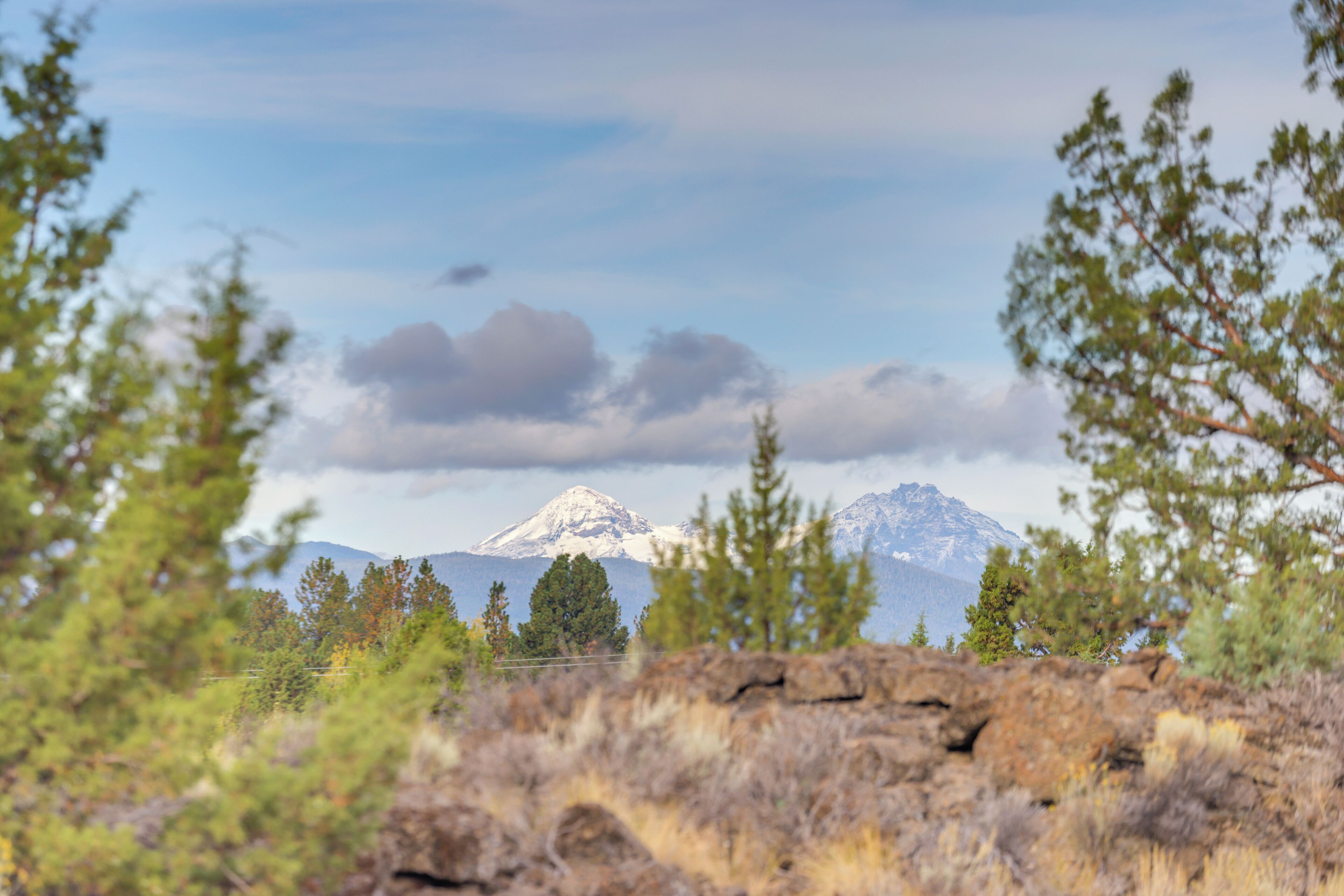 Un paisaje montañoso con un pico destacado, rodeado de árboles y terreno rocoso.