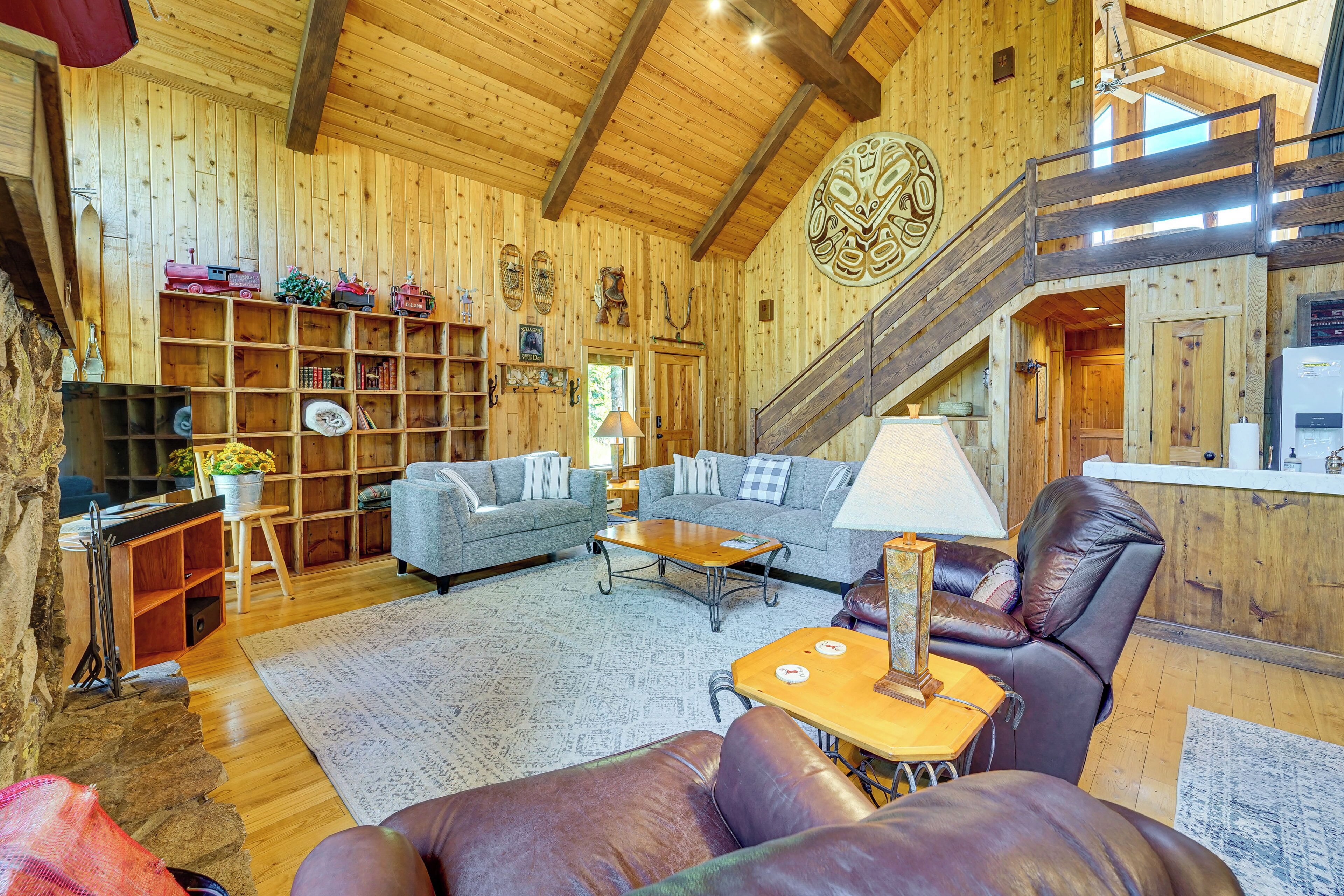 Un interior de madera con un sofá, sillones, una mesa de centro y una escalera.