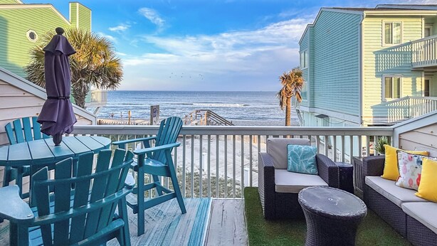 A balcony with a view of the ocean, featuring outdoor furniture and a railing. - Poolside Fun + Oceanfront Bliss: Kure Beach Haven! (Kure Beach)
