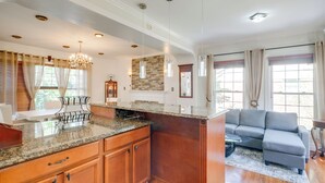 A spacious living area with a large grey sectional sofa, a kitchen island with granite countertop, wooden cabinets, and pendant lighting. - Take Metro to DC! Family Home in Springfield (Springfield)