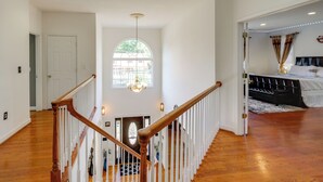A spacious room with a wooden staircase, a chandelier, and a view through a large arched window. - Take Metro to DC! Family Home in Springfield (Springfield)
