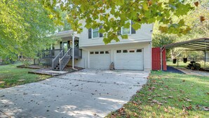 Ein zweistöckiges Haus mit überdachter Garage und einer Veranda.