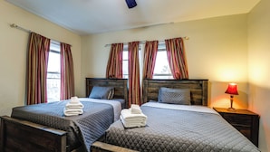 Une chambre d’hôtel avec deux lits, une tête de lit en bois, une table de chevet avec une lampe et une fenêtre avec des rideaux.