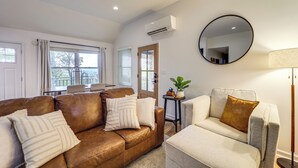 A modern living room with a brown leather sofa, a grey armchair, and a small side table with a plant.