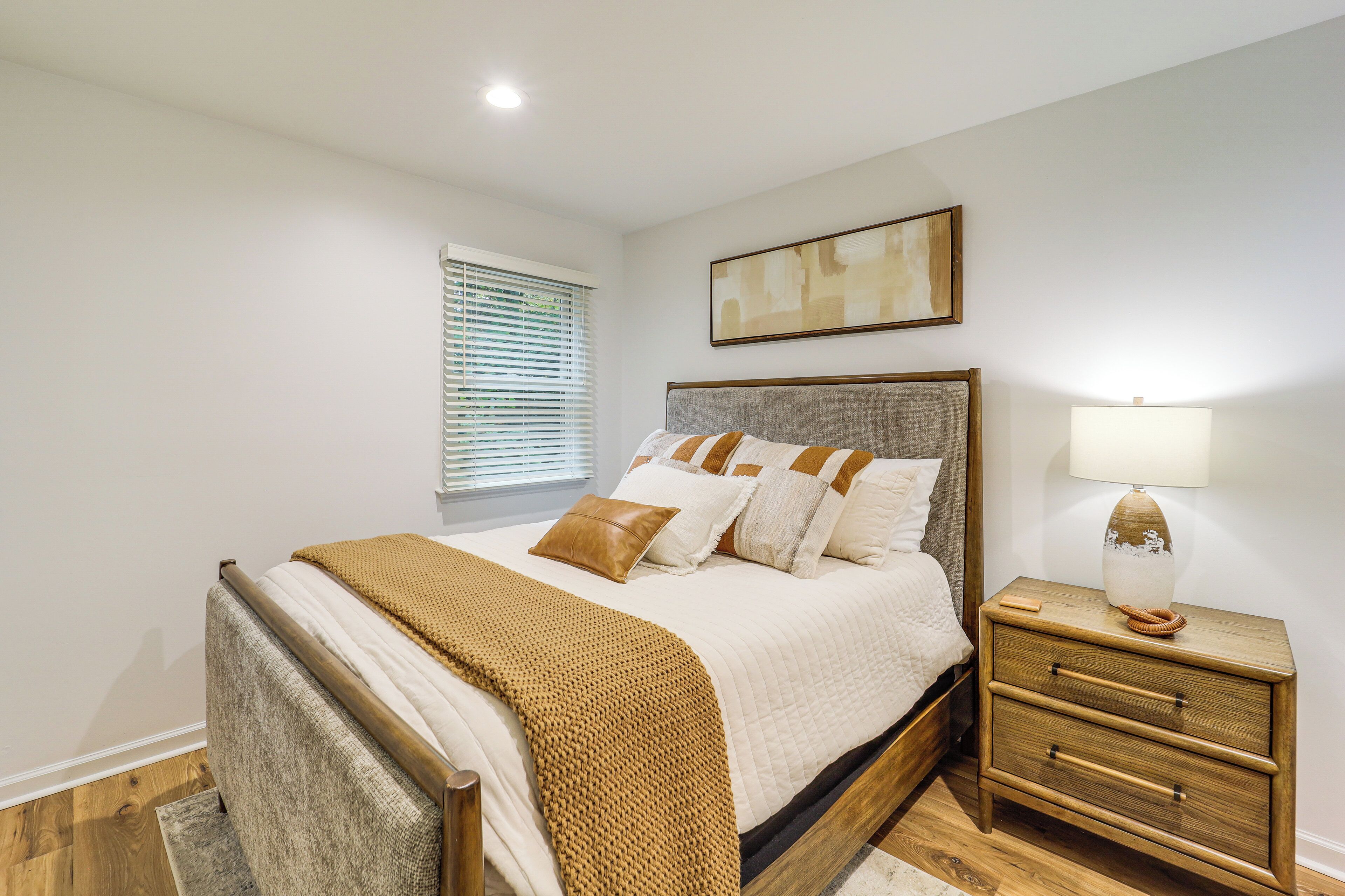 Un dormitorio con cama, mesita de noche y lámpara.