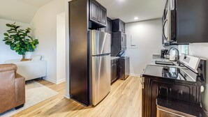 A modern kitchen with stainless steel appliances, wooden flooring, and a built-in oven.