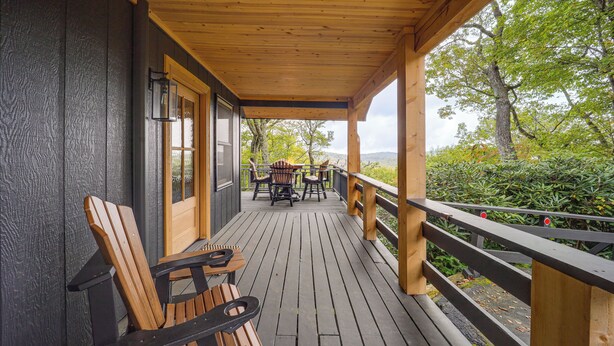 A wooden deck with a railing, a table with chairs, and a bench.