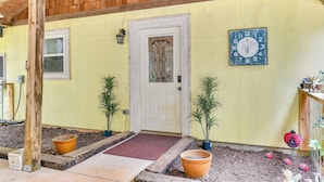 A yellow building with a white door, a clock, and potted plants. - Forested Family Hideaway Near Lake Sinclair! (Eatonton)