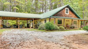 A rustic cabin with a covered porch, a welcome sign, and a flag. - Forested Family Hideaway Near Lake Sinclair! (Eatonton)