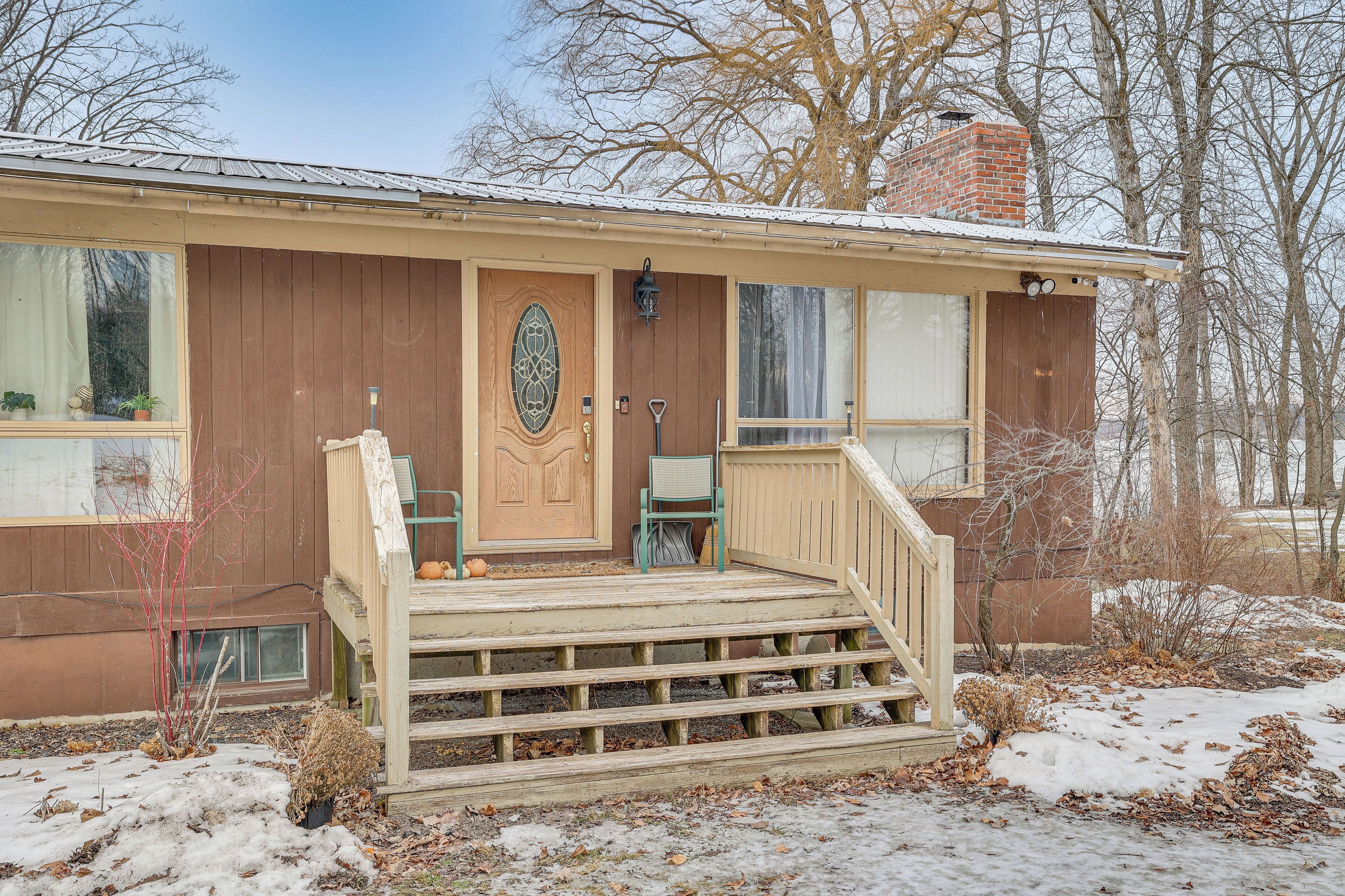 A single-story house with a front porch, a wooden door, and a small set of steps leading to the entrance.
