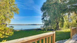 Una terraza de madera con vistas a un lago y un área verde con árboles.
