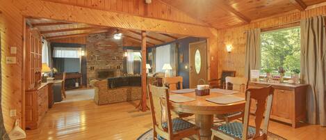 Un interior de madera con comedor, chimenea y vistas al exterior.