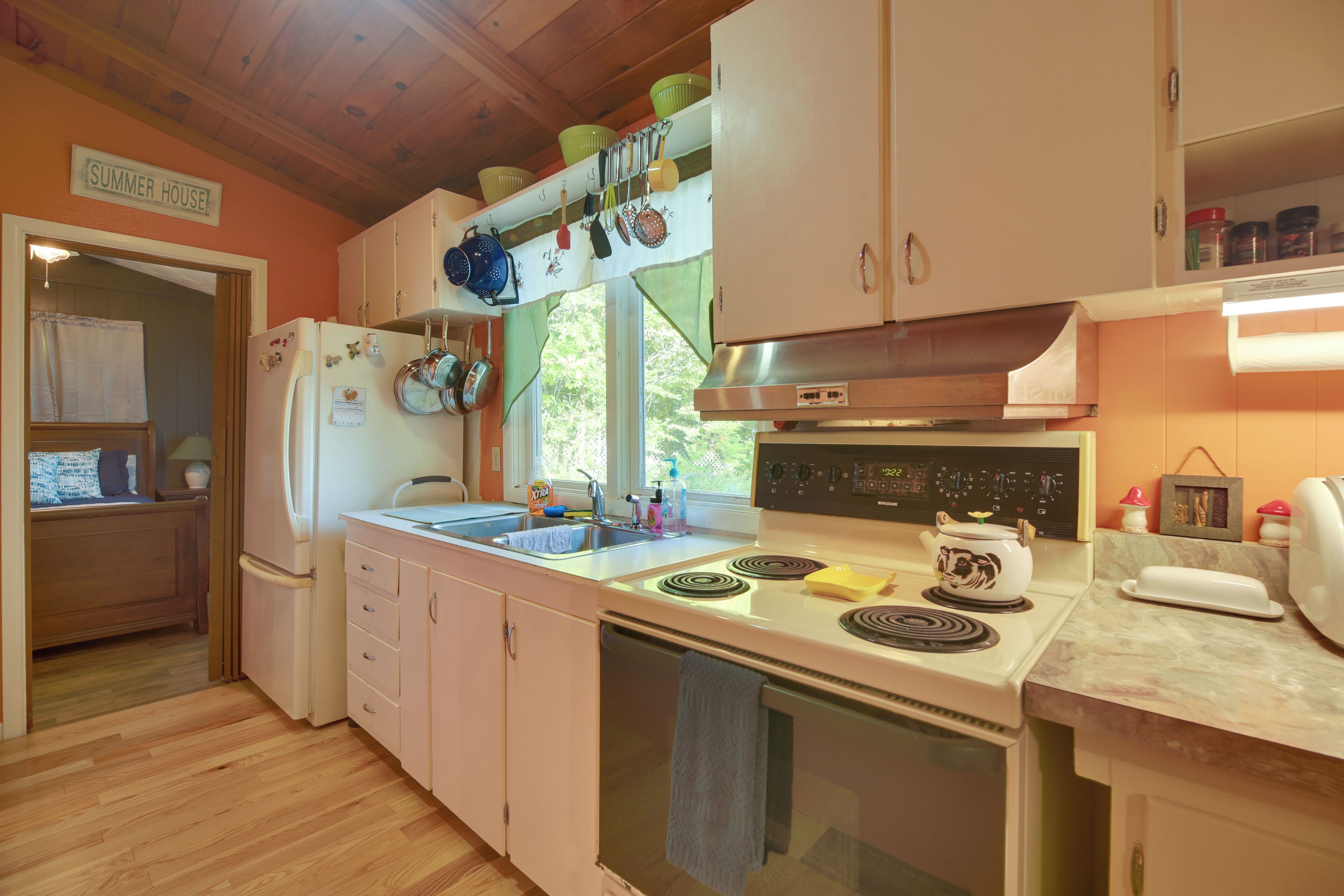 A compact kitchen with wooden cabinets, a refrigerator, a stove, and a sink.