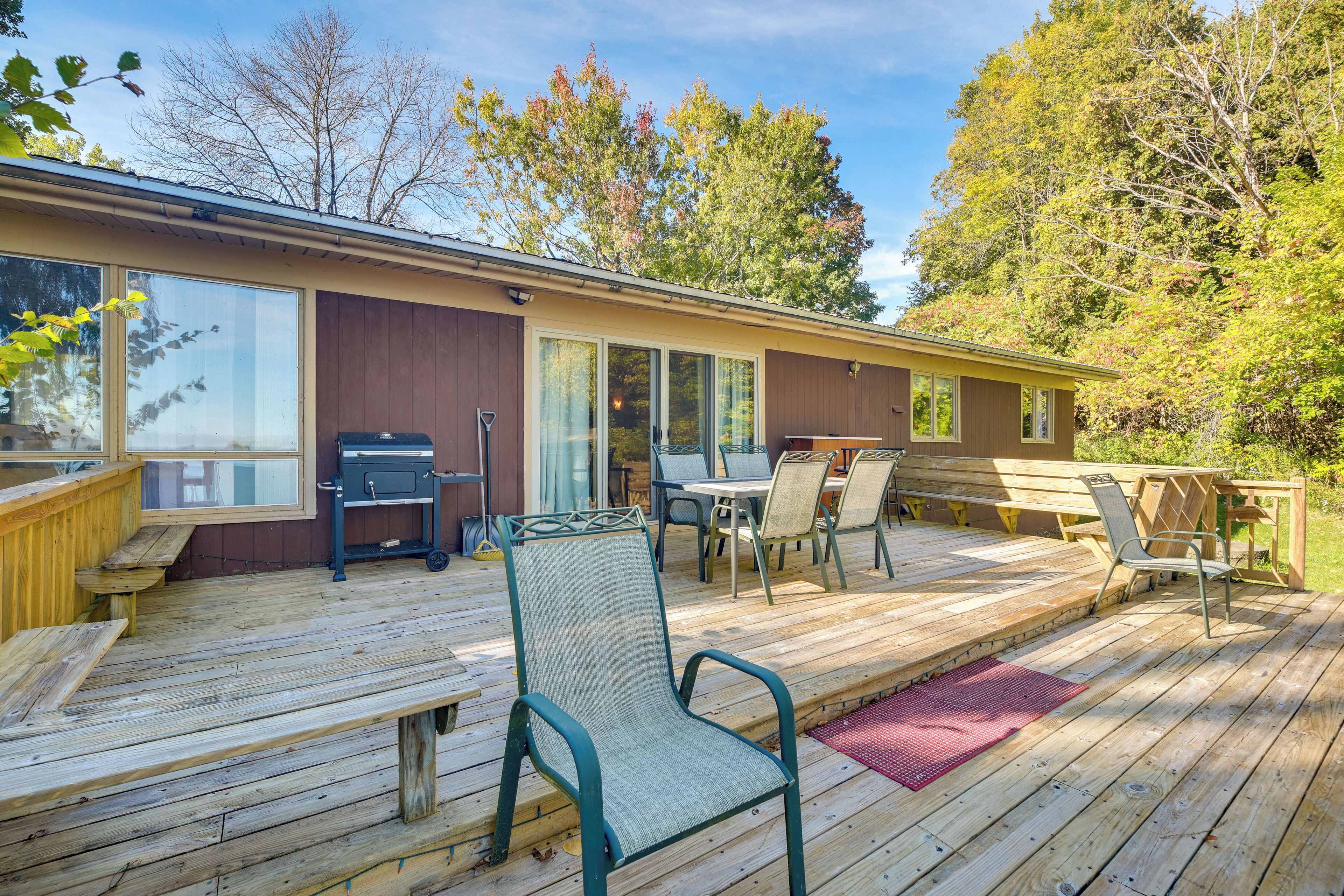 A wooden deck with outdoor furniture, including chairs and a table, and a barbecue grill.