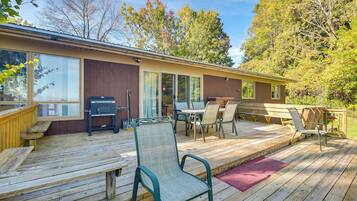 A wooden deck with outdoor furniture, including chairs and a table, and a barbecue grill.