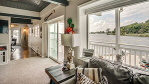 Un accogliente soggiorno con vista sul fiume, soffitto in legno e un divano con un cuscino decorativo.