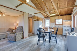 A spacious living area with a sofa and armchair, a dining table with chairs, and a kitchen with wooden cabinets and appliances. - Indian River Fall Escape: Fire Pit & Lake Views (Indian River)