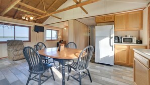 A spacious kitchen with wooden cabinets, a dining table with chairs, and a large window overlooking a body of water. - Mullett Lake Cabin w/ Private Dock & Fire Pit! (Indian River)