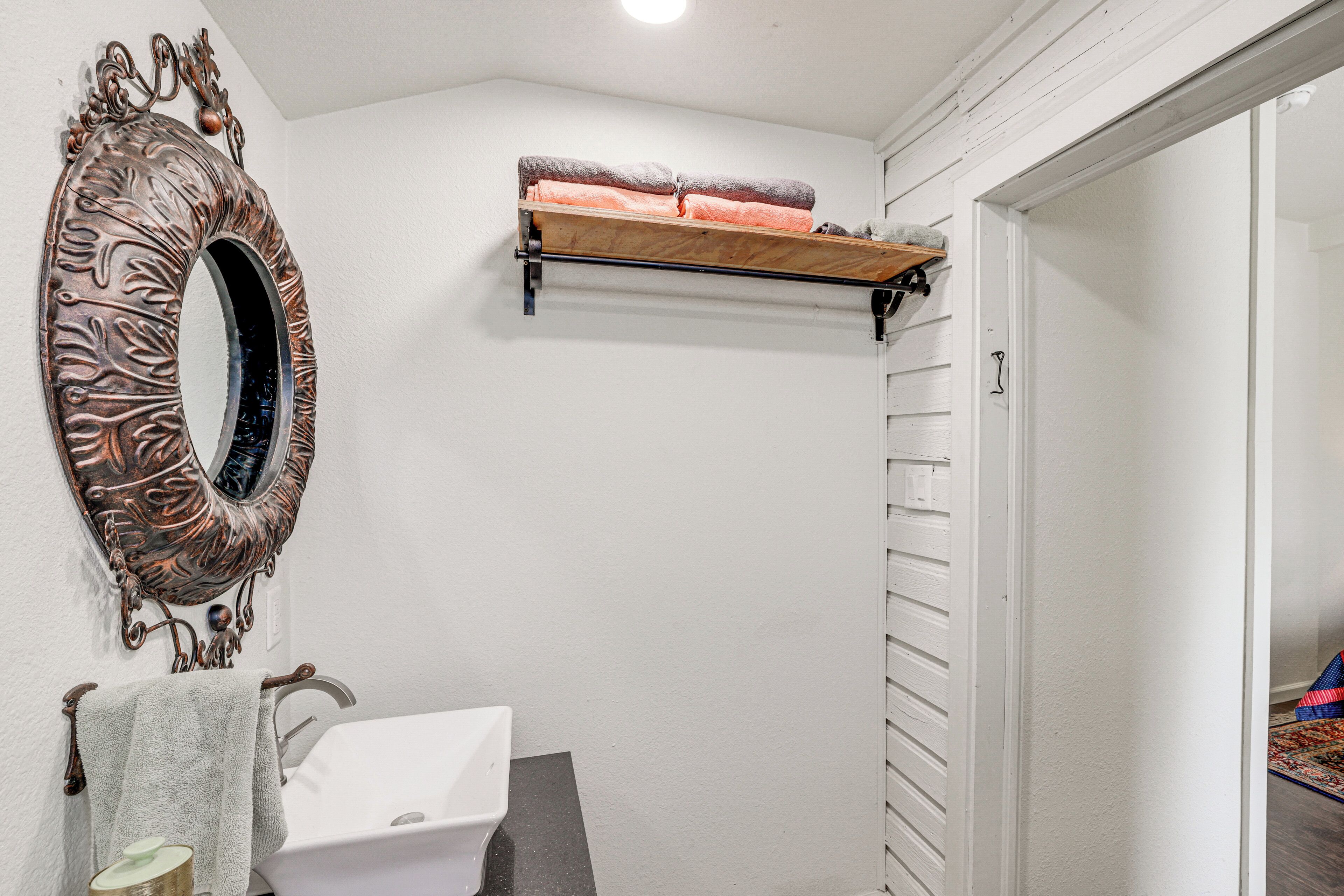 A bathroom with a white sink, a decorative mirror, and a towel rack.