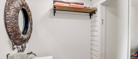 A bathroom with a white sink, a decorative mirror, and a towel rack.