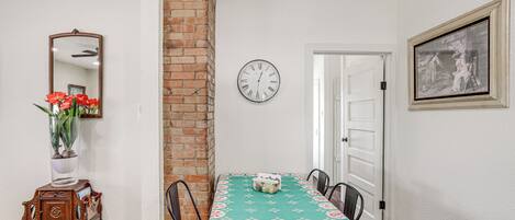 A dining area with a brick wall, a clock, and a table with chairs.