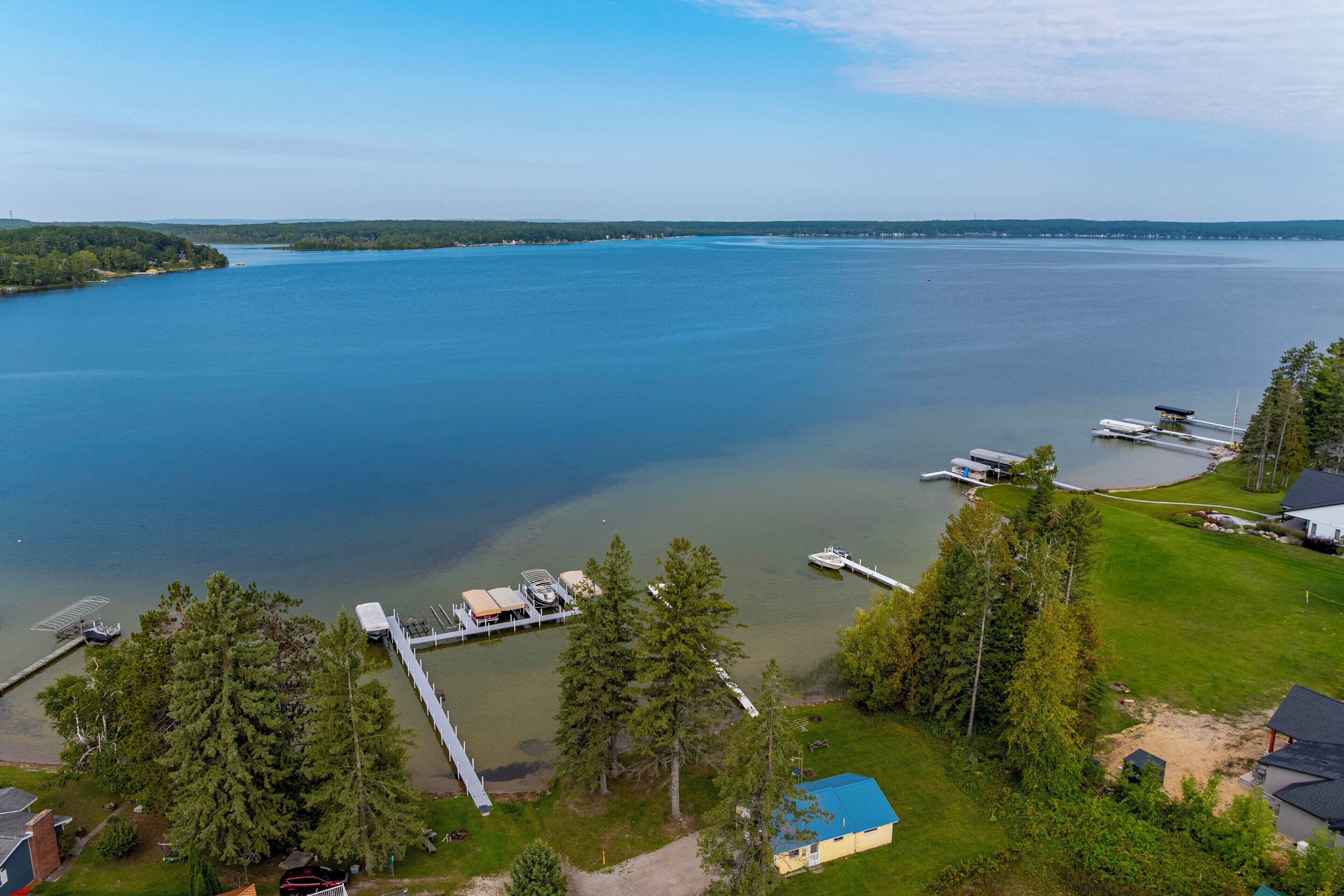 An aerial view of a lakeside property with docks, a boat, and a small building.