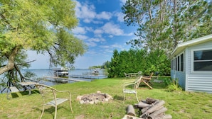 A lakeside cabin with a fire pit, outdoor seating, and a dock extending into the water. - Waterfront Mullett Lake Cabin: Pets Welcome! (Indian River)
