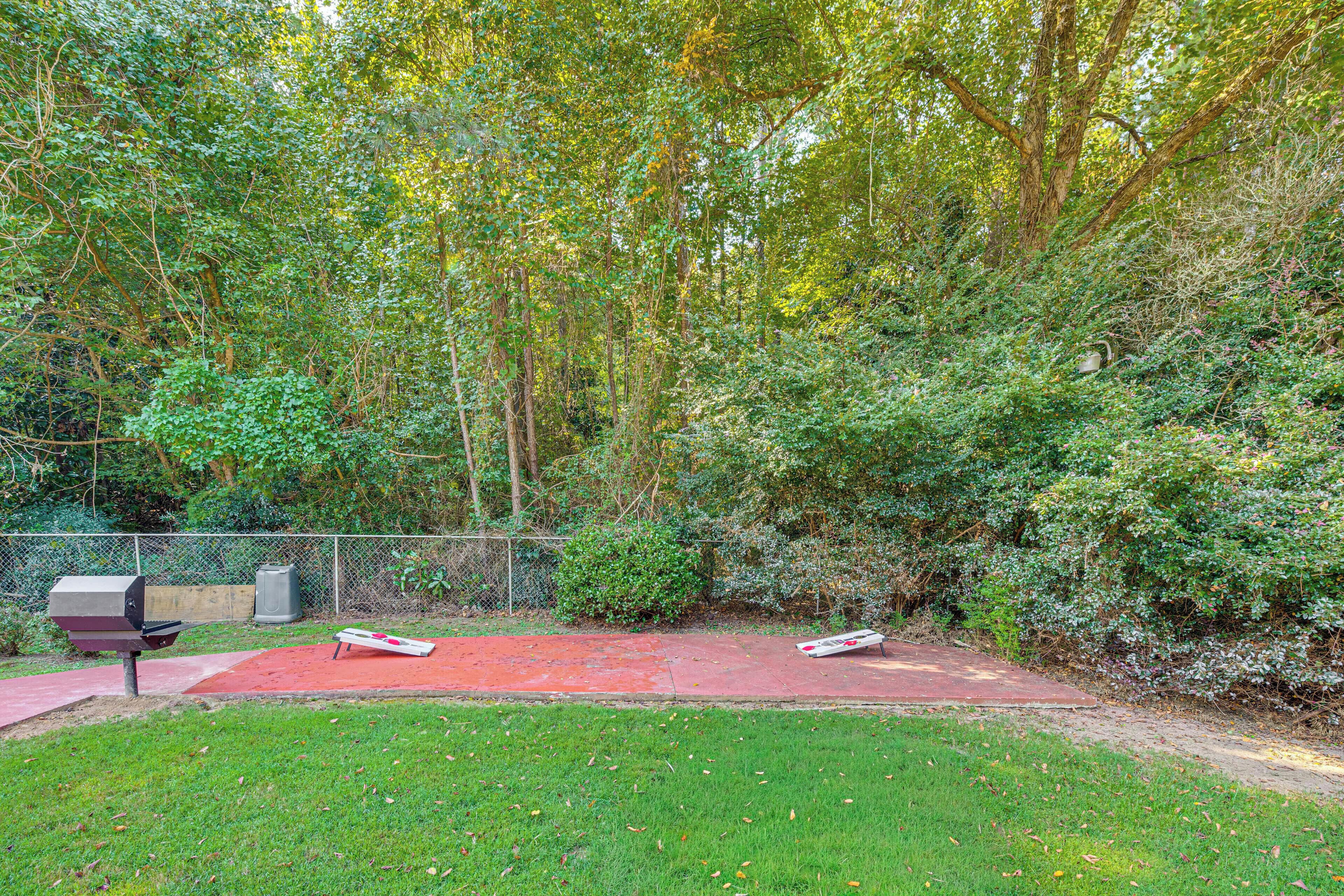 A backyard with a red rubber surface, a grill, and a fence.