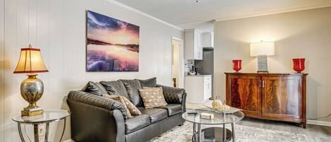 A living room with a leather sofa, a glass coffee table, a wooden cabinet, and a painting on the wall.