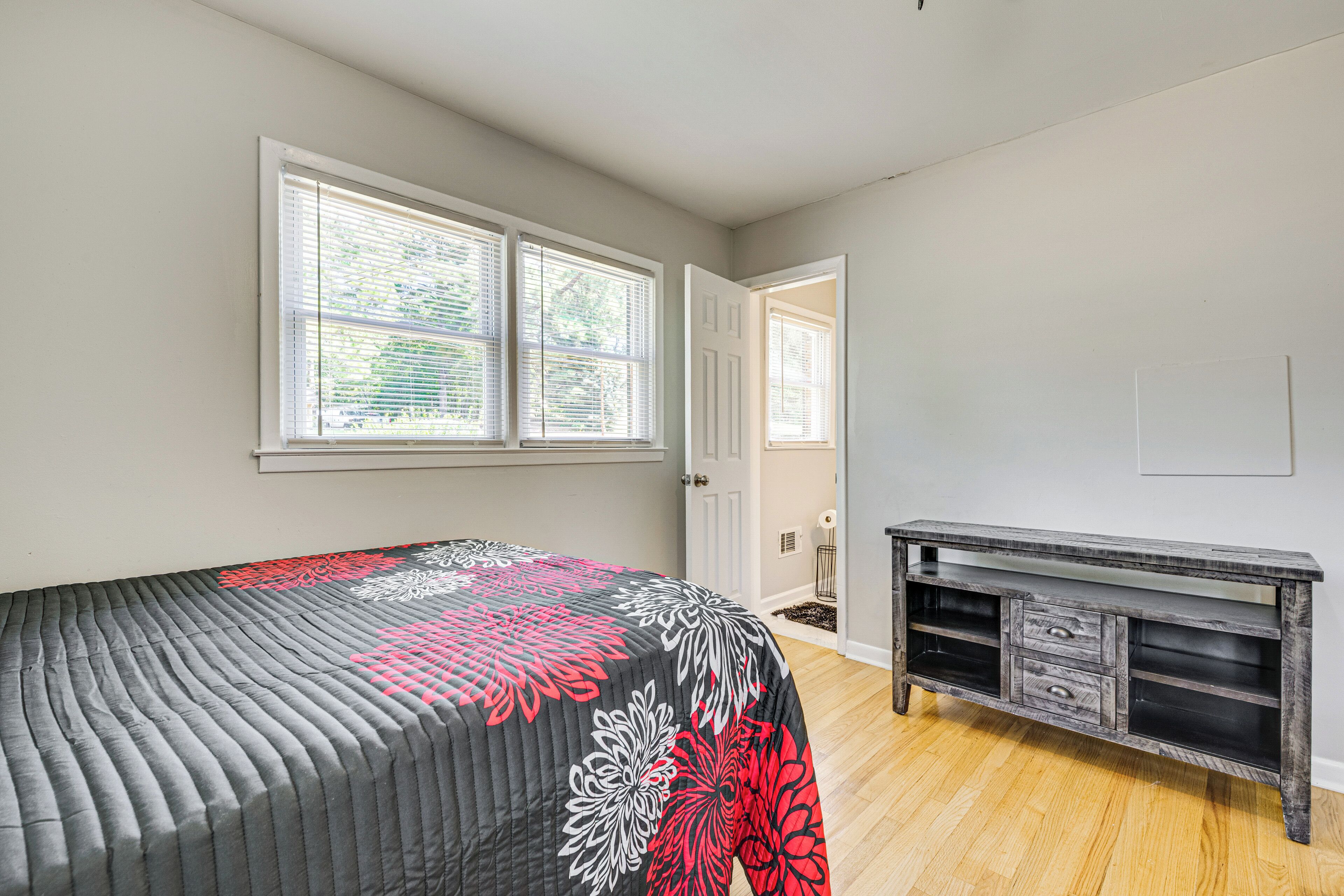 Un dormitorio con cama, cómoda y dos ventanas.