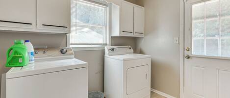 A laundry room with a washer, dryer, and a bucket.
