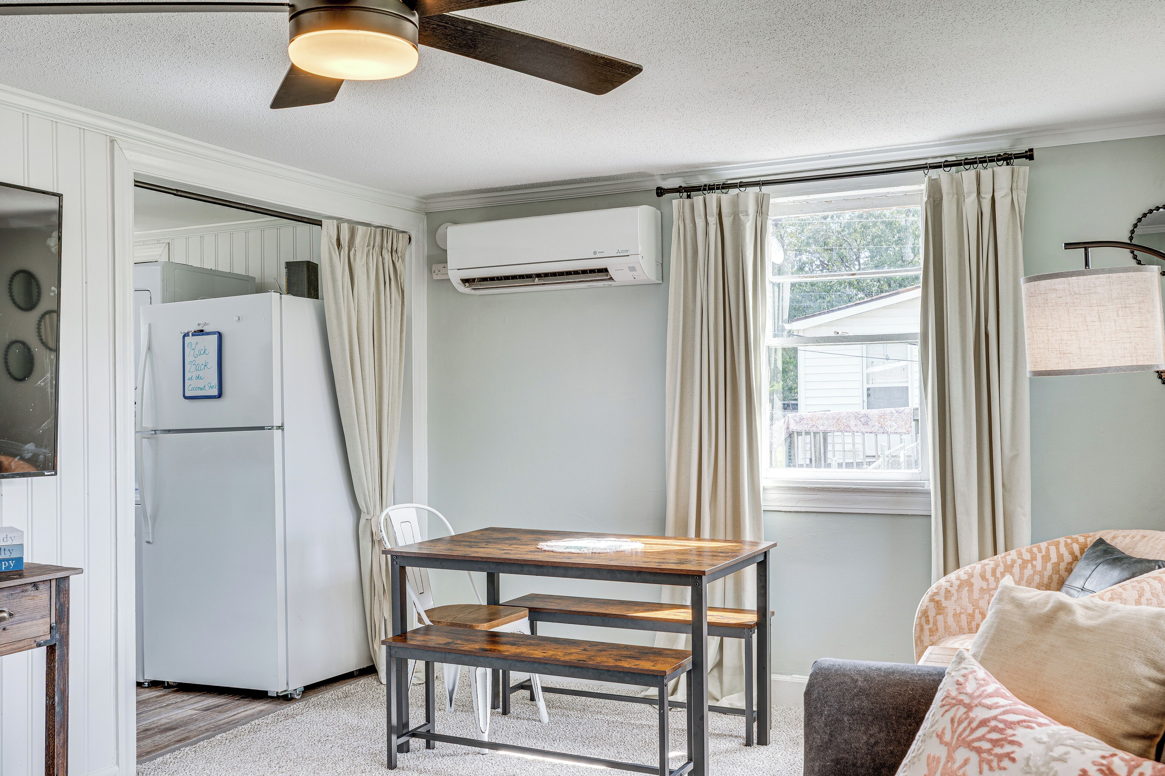 A compact living space with a kitchenette, a dining area, and a window with curtains.