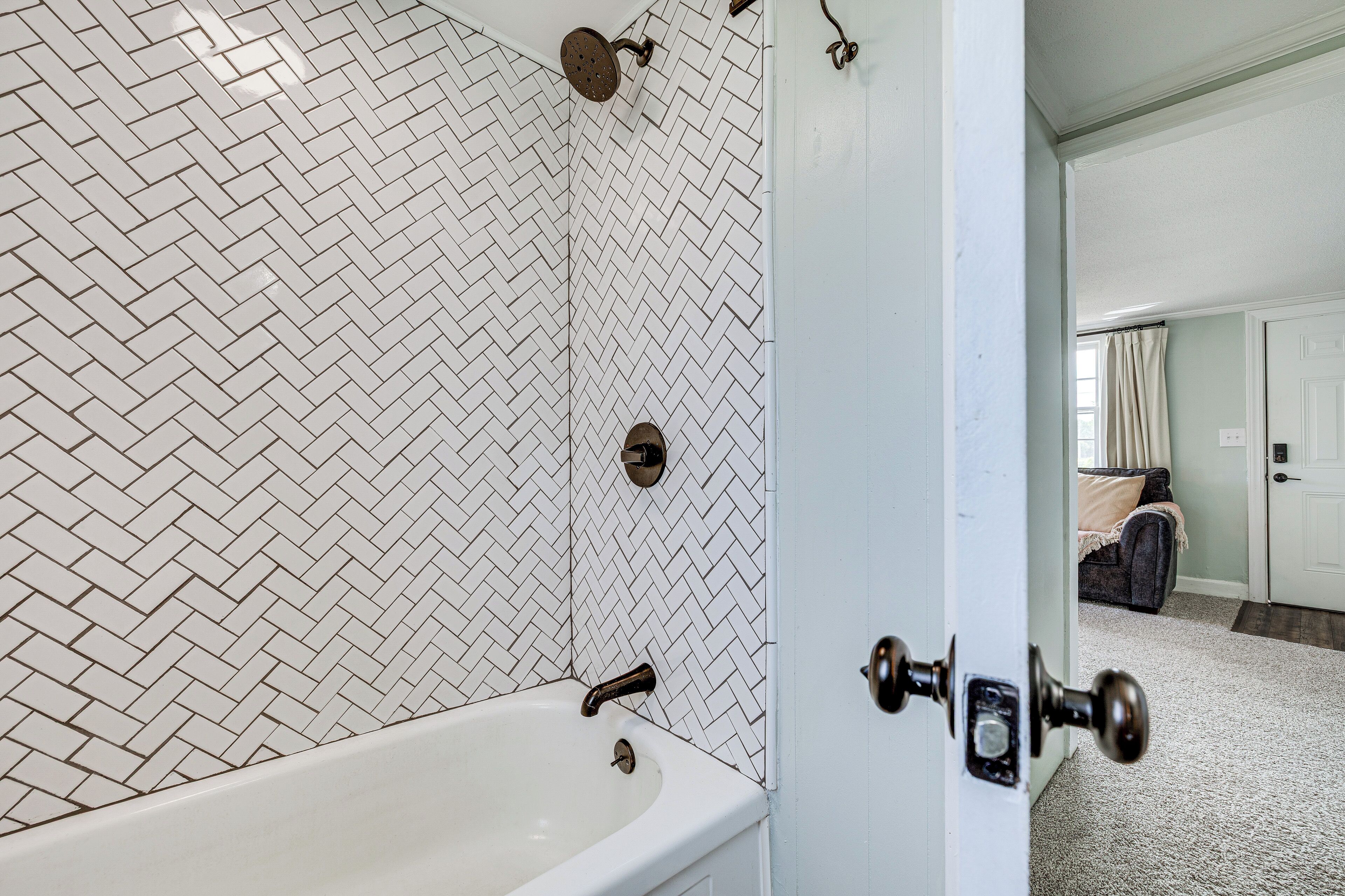 A bathroom with a herringbone tile pattern, a bathtub, and a shower with a round head.