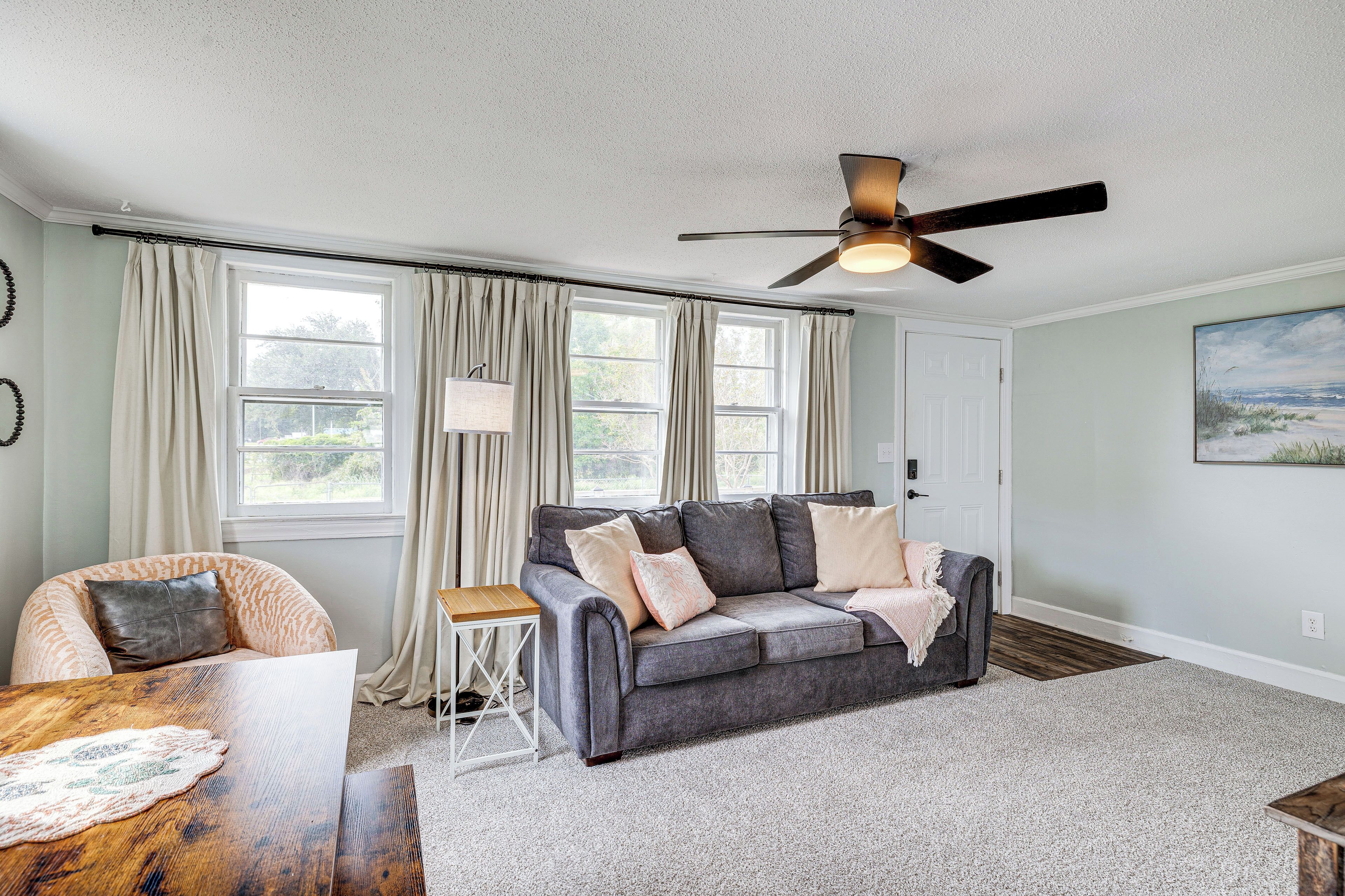 A living room with a grey sofa, a wooden coffee table, and a ceiling fan.