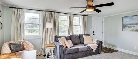 A living room with a grey sofa, a wooden coffee table, and a ceiling fan.
